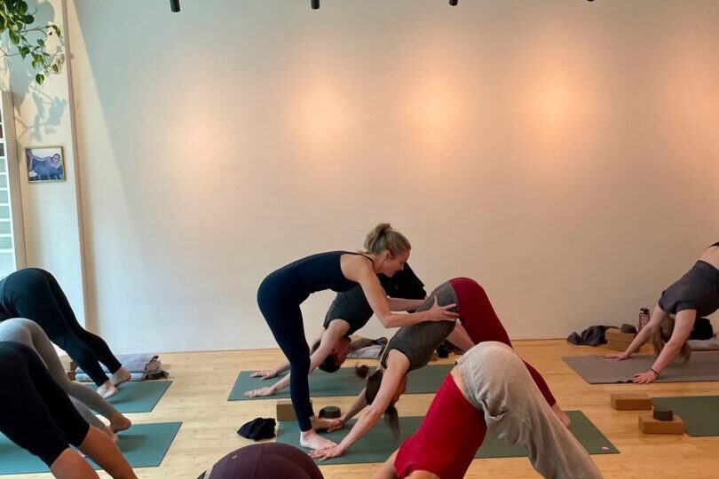 A teacher providing hands-on assistance during a group yoga class