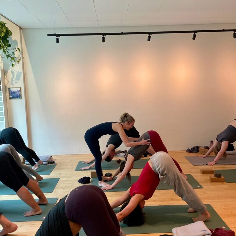 Teacher giving a hands-on assist during a group yoga class